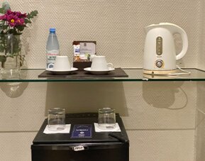 In-room refreshment station featuring complimentary bottled water, tea and coffee facilities, glassware, and a compact minibar for guest convenience at Hotel Lafayette.