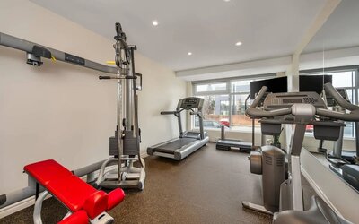 Modern fitness centre with cardio machines and strength training equipment at Hotel Brossard.
