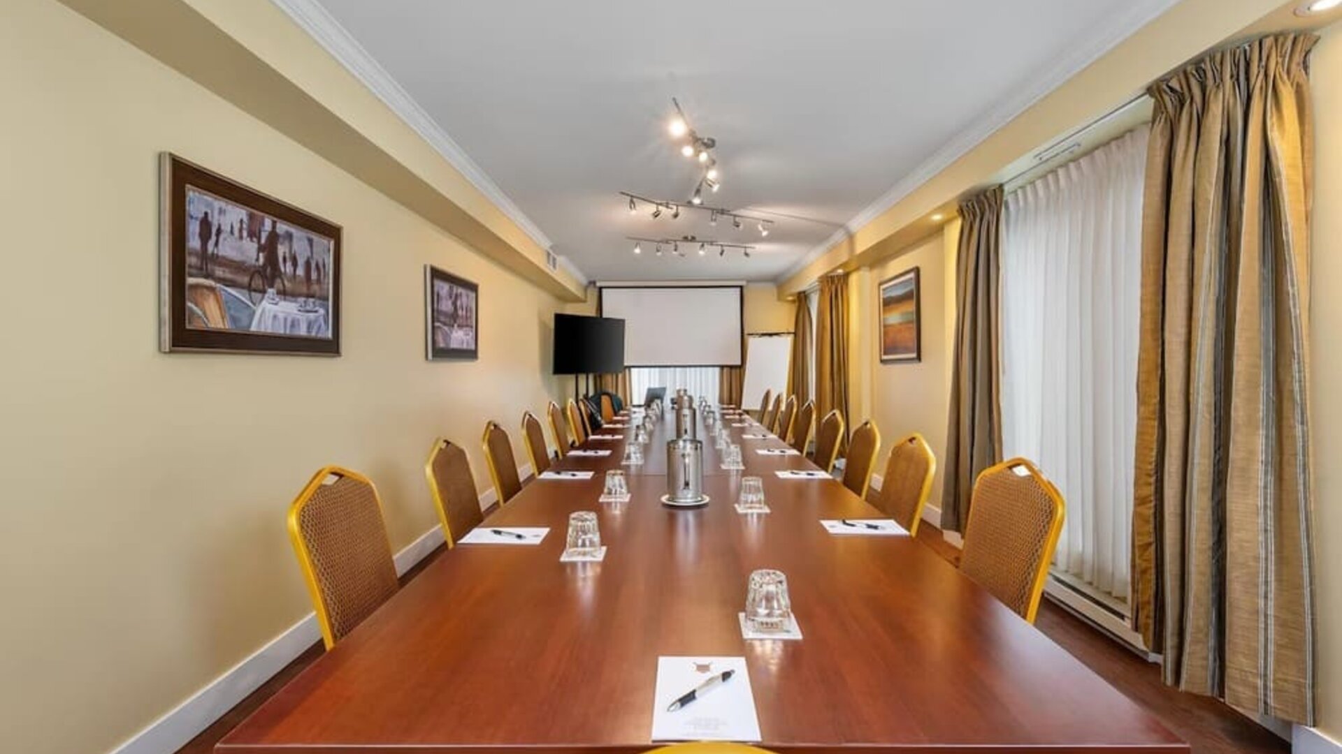 Spacious conference room with boardroom layout and audiovisual presentation facilities at Hotel Brossard.