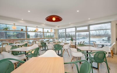 Bright dining area with floor-to-ceiling windows and contemporary seating at Hotel Brossard.