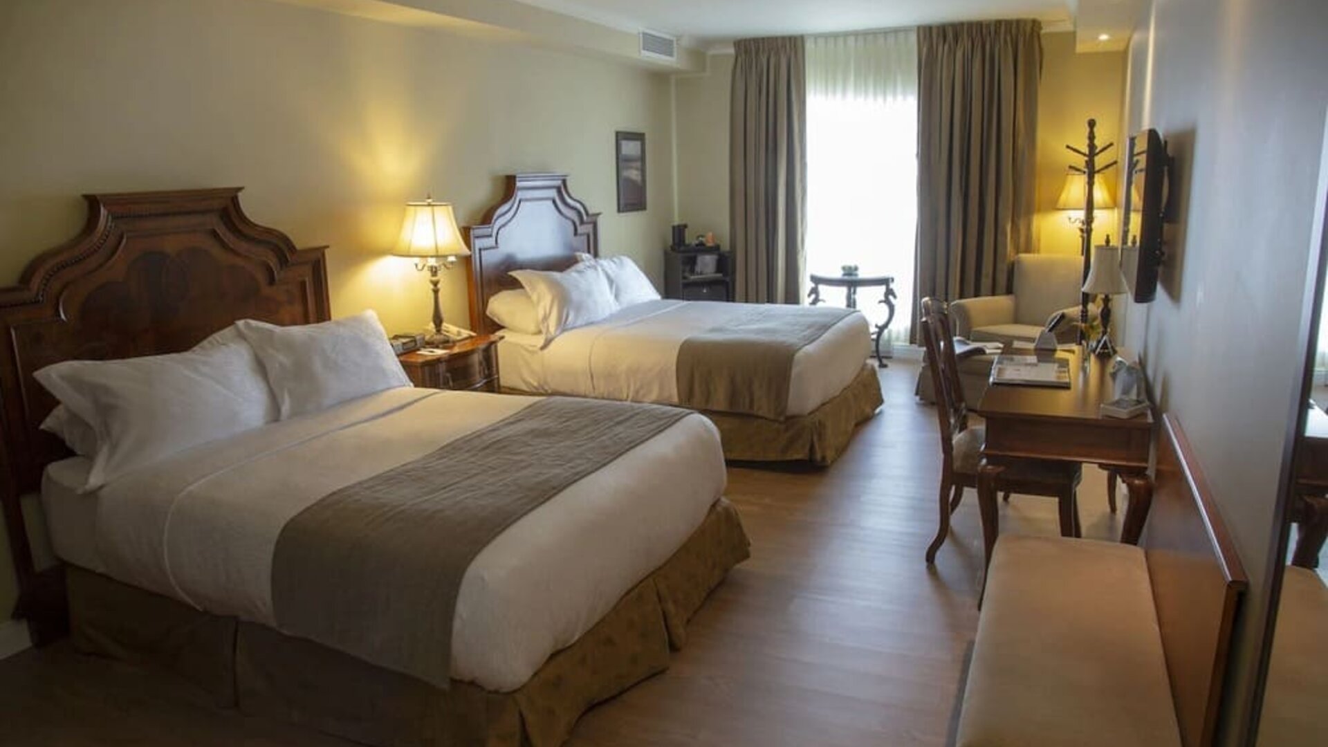 ontemporary guest room featuring two queen beds, workspace and modern amenities at Hotel Brossard.