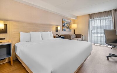 Bright king guest room with comfortable seating, work desk and modern furnishings at Comfort Inn Laval.