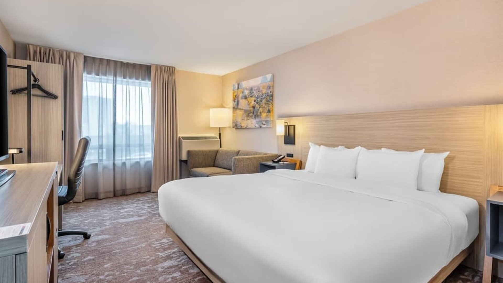 Modern king guest room with workspace, sofa and comfortable amenities at Comfort Inn Laval.