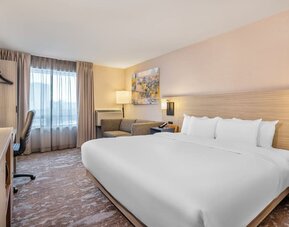 Modern king guest room with workspace, sofa and comfortable amenities at Comfort Inn Laval.