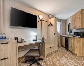Guest room workspace with desk, kitchenette, microwave, mini fridge and coffee station at Comfort Inn Laval.