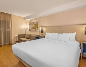 Comfortable king guest room with sofa seating and modern amenities at Comfort Inn Laval.