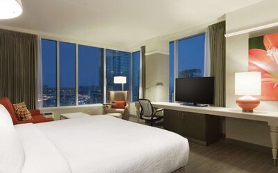 Spacious king guest room with floor-to-ceiling windows, city views, workspace and comfortable seating at Hilton Garden Inn Calgary Downtown.