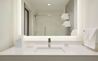 Modern guest bathroom with illuminated vanity, walk-in shower and contemporary finishes at Hilton Garden Inn Calgary Downtown.