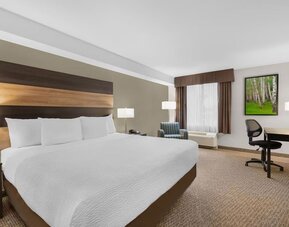Comfortable king guest room with workspace, armchair and modern amenities at Days Inn & Suites By Wyndham Lindsay.