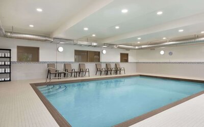 Spacious indoor swimming pool with easy-entry steps and poolside seating at Days Inn & Suites By Wyndham Lindsay.