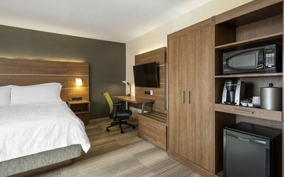Modern king guest room featuring a work desk, mini fridge, microwave, coffee maker and flat-screen TV at Holiday Inn Express Toronto Downtown.