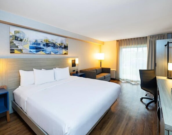 Comfortable king guest room featuring a bright workspace, sofa, and large flat-screen TV at Comfort Inn Sydney.