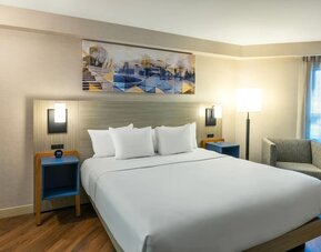 Inviting king bed with premium linens, bedside lighting, and cozy armchair for a relaxing stay at Comfort Inn Amherst.