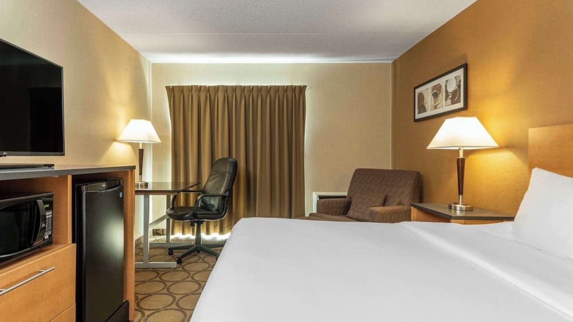Spacious king guest room featuring premium bedding, microwave, mini fridge, work desk, and comfortable seating at Comfort Inn Thetford Mines.