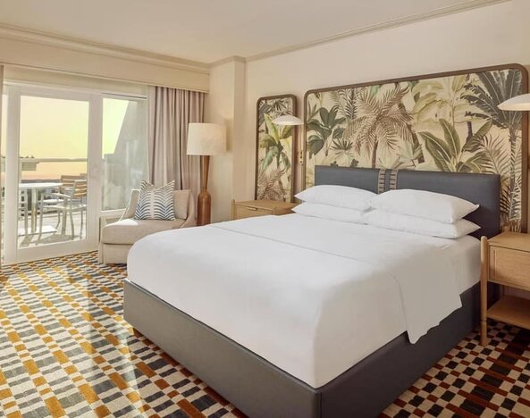 Stylish king guest room featuring plush bedding, private balcony, comfortable seating, and coastal-inspired décor at Hyatt Centric Delfina Santa Monica.