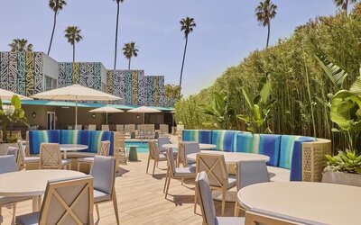 Outdoor poolside patio with comfortable seating, dining tables, and relaxing spaces to enjoy the Southern California sunshine at Hyatt Centric Delfina Santa Monica.