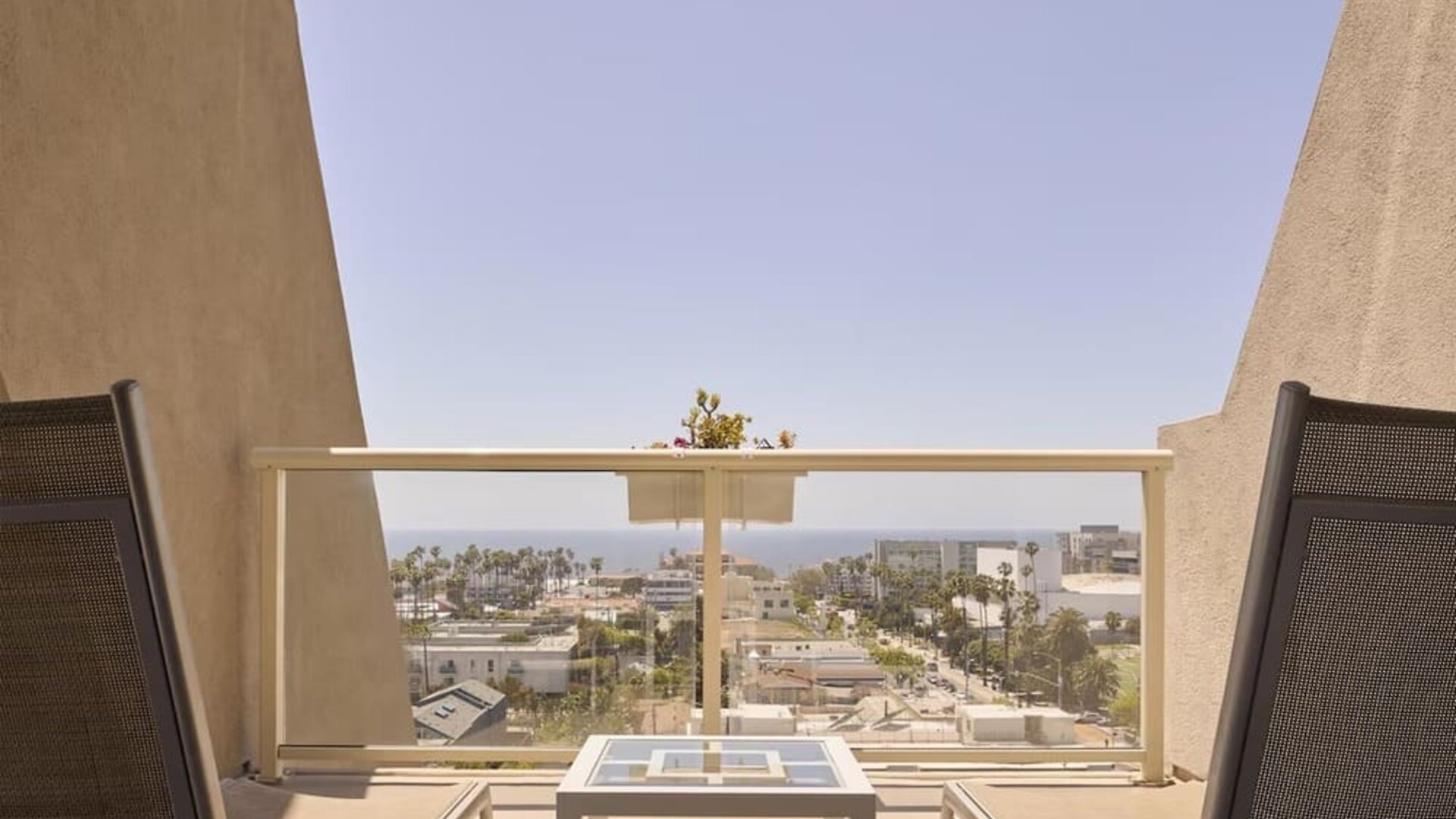 Private guest room balcony with comfortable seating and scenic views of Santa Monica and the Pacific coastline at Hyatt Centric Delfina Santa Monica.