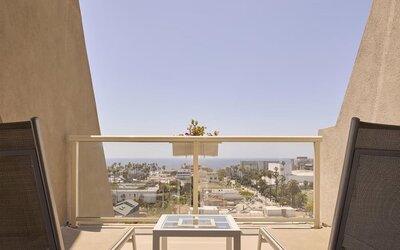 Private guest room balcony with comfortable seating and scenic views of Santa Monica and the Pacific coastline at Hyatt Centric Delfina Santa Monica.