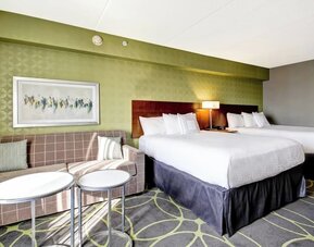 Comfortable guest room featuring two queen beds, a sofa, and modern décor at Fairfield Inn & Suites Guelph.