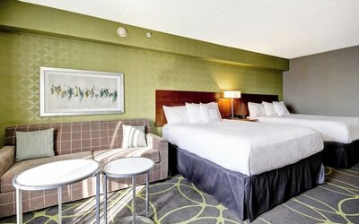 Comfortable guest room featuring two queen beds, a sofa, and modern décor at Fairfield Inn & Suites Guelph.