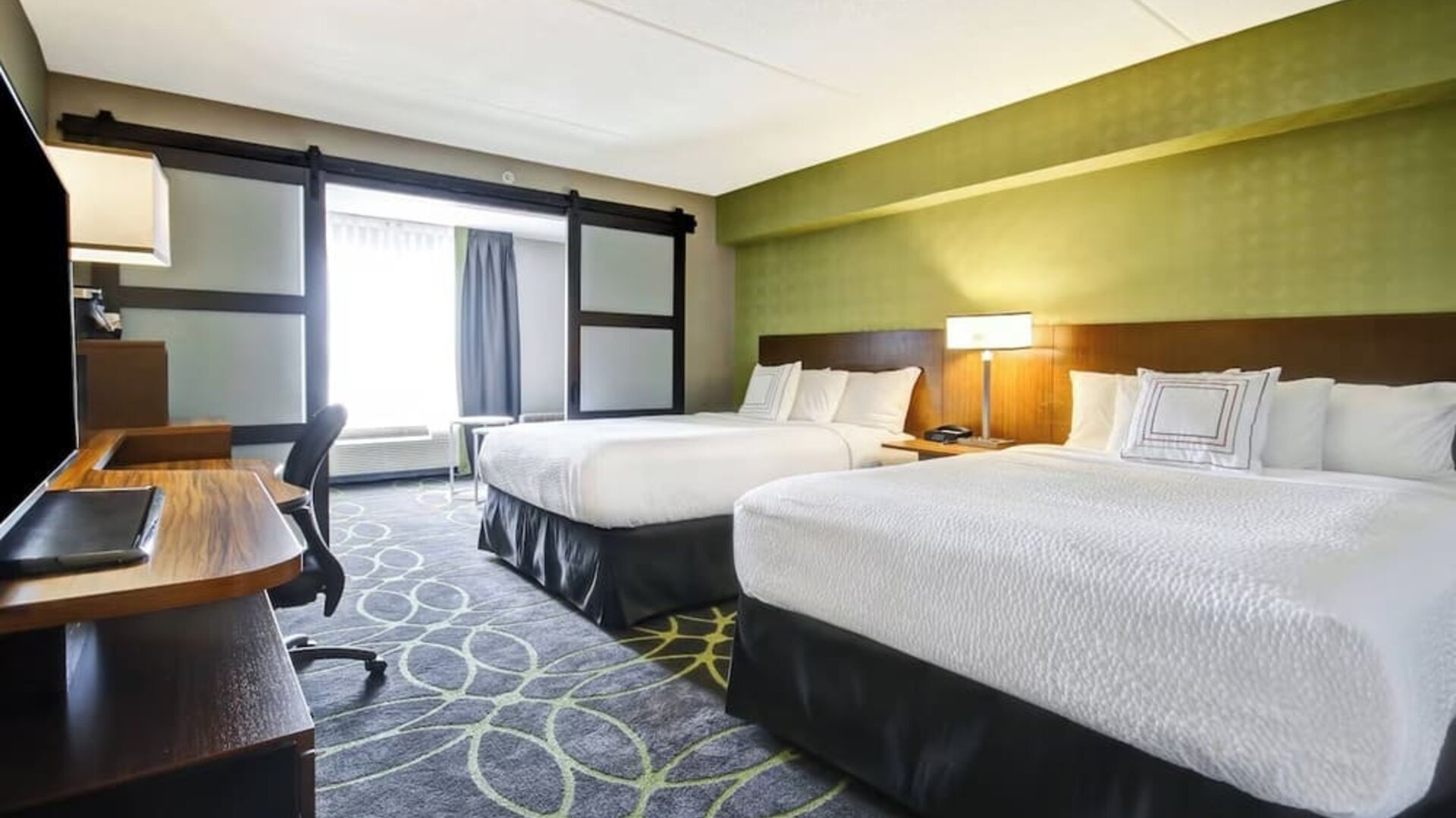 Comfortable guest room featuring two queen beds, modern décor, and convenient in-room workspace at Fairfield Inn & Suites Guelph.