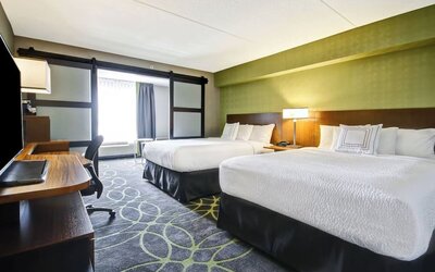 Comfortable guest room featuring two queen beds, modern décor, and convenient in-room workspace at Fairfield Inn & Suites Guelph.