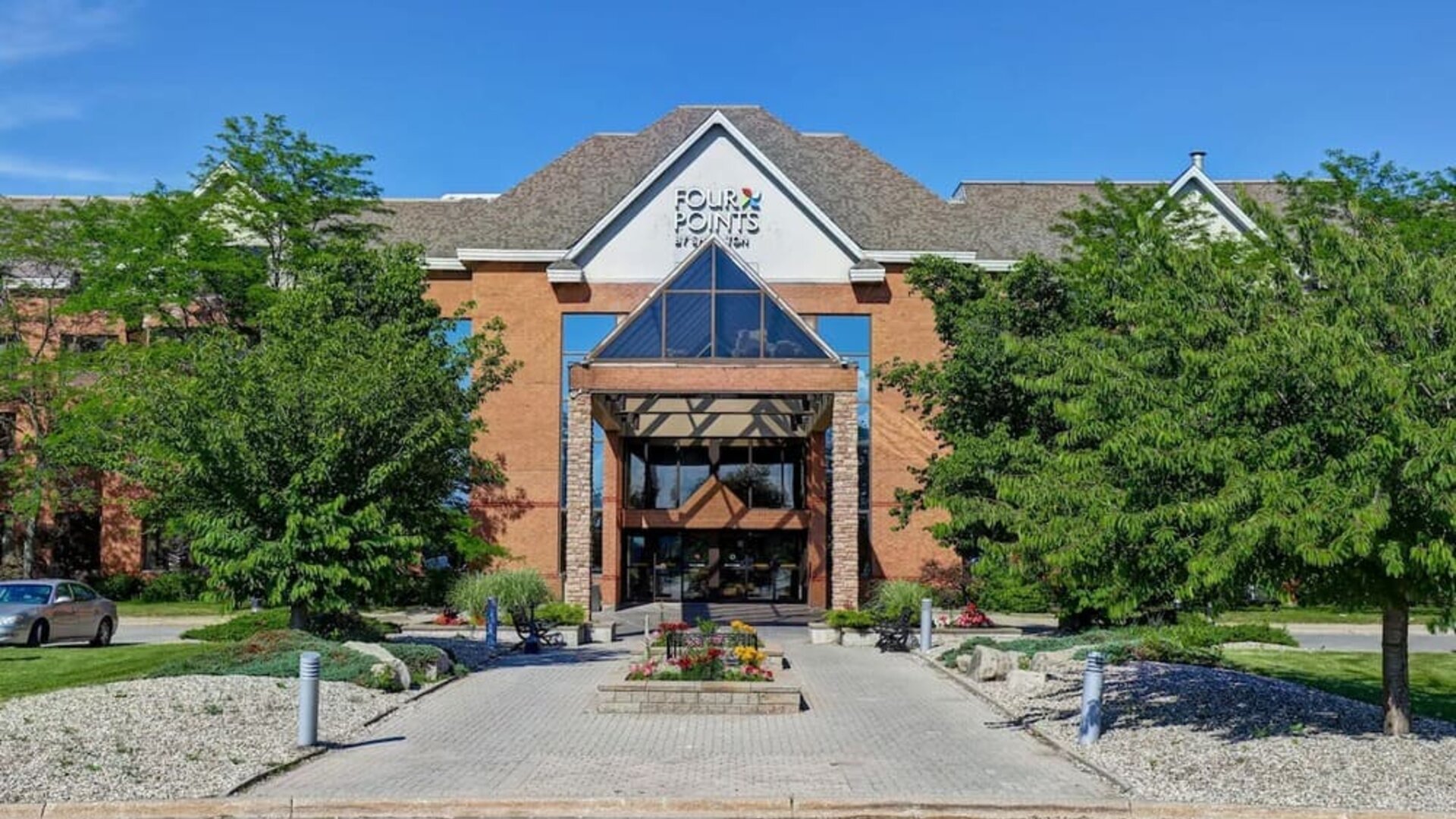 Welcoming hotel entrance surrounded by landscaped gardens at Four Points by Sheraton St. Catharines Niagara Suites.