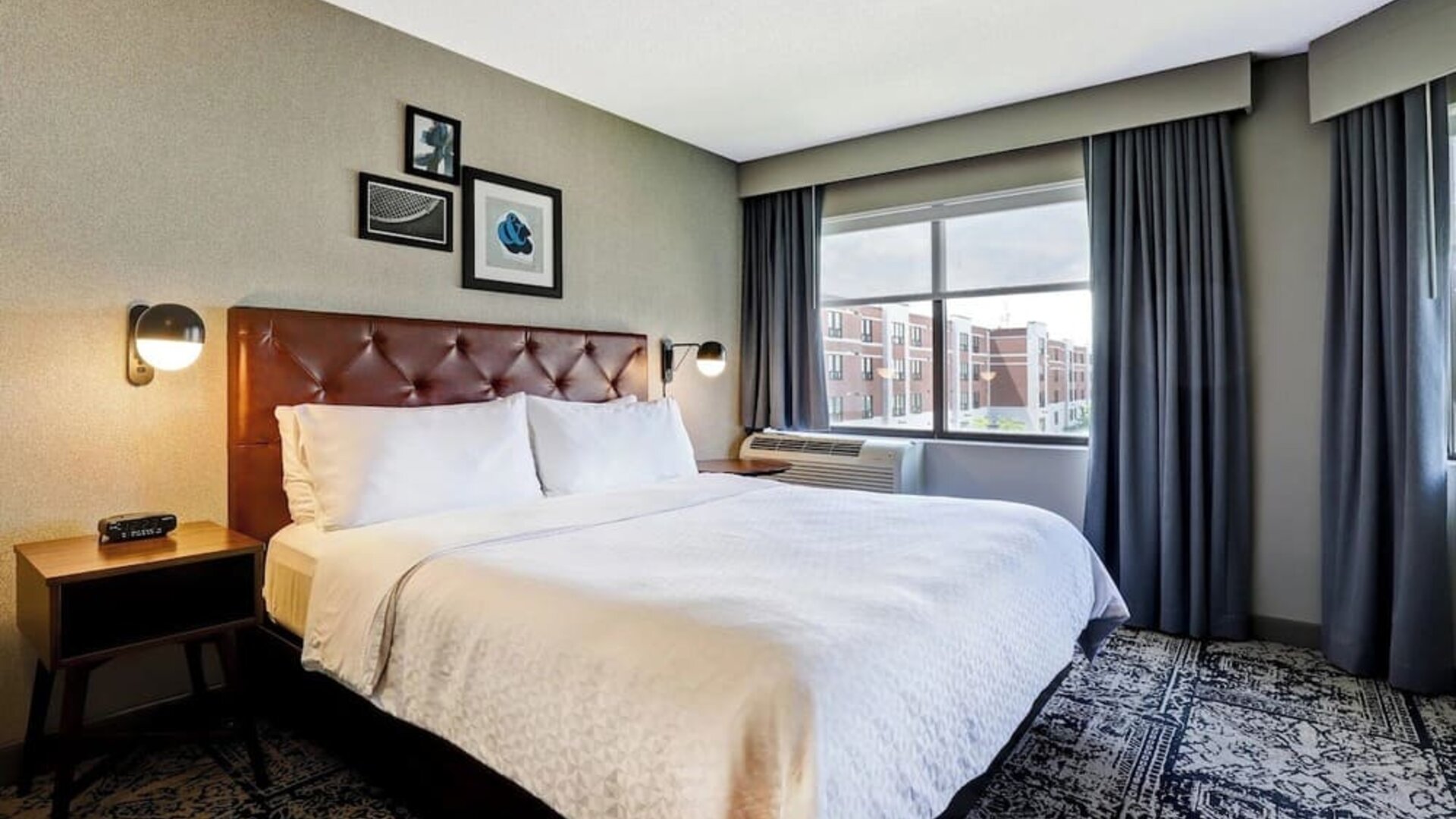 Contemporary king guest room featuring plush bedding, large windows, and modern décor at Four Points by Sheraton St. Catharines Niagara Suites.