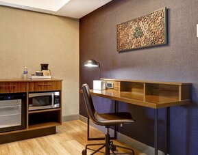 Functional in-room workspace with ergonomic desk, mini refrigerator, microwave, and coffee station at Four Points by Sheraton St. Catharines Niagara Suites.
