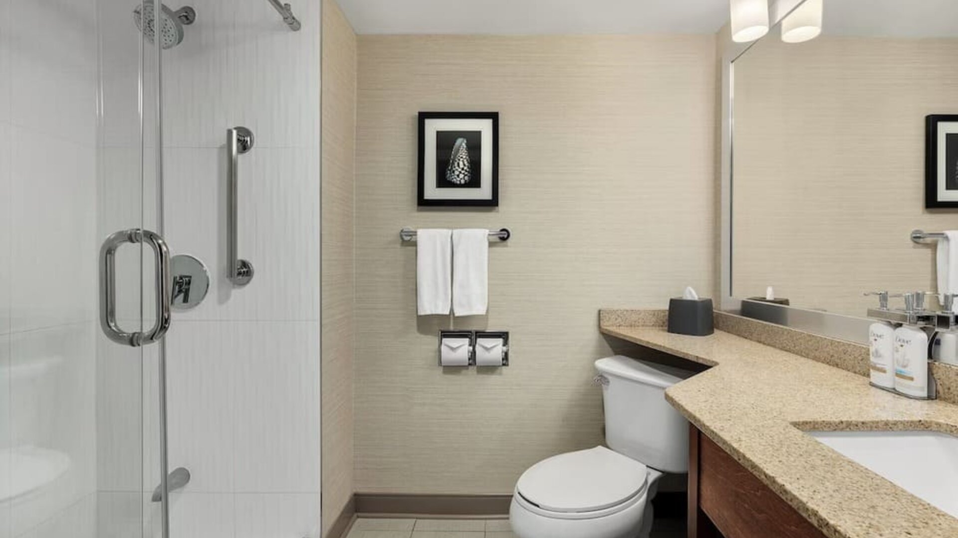 Modern guest bathroom featuring a glass-enclosed walk-in shower, spacious vanity, and premium bath amenities at Holiday Inn Oakville Centre.