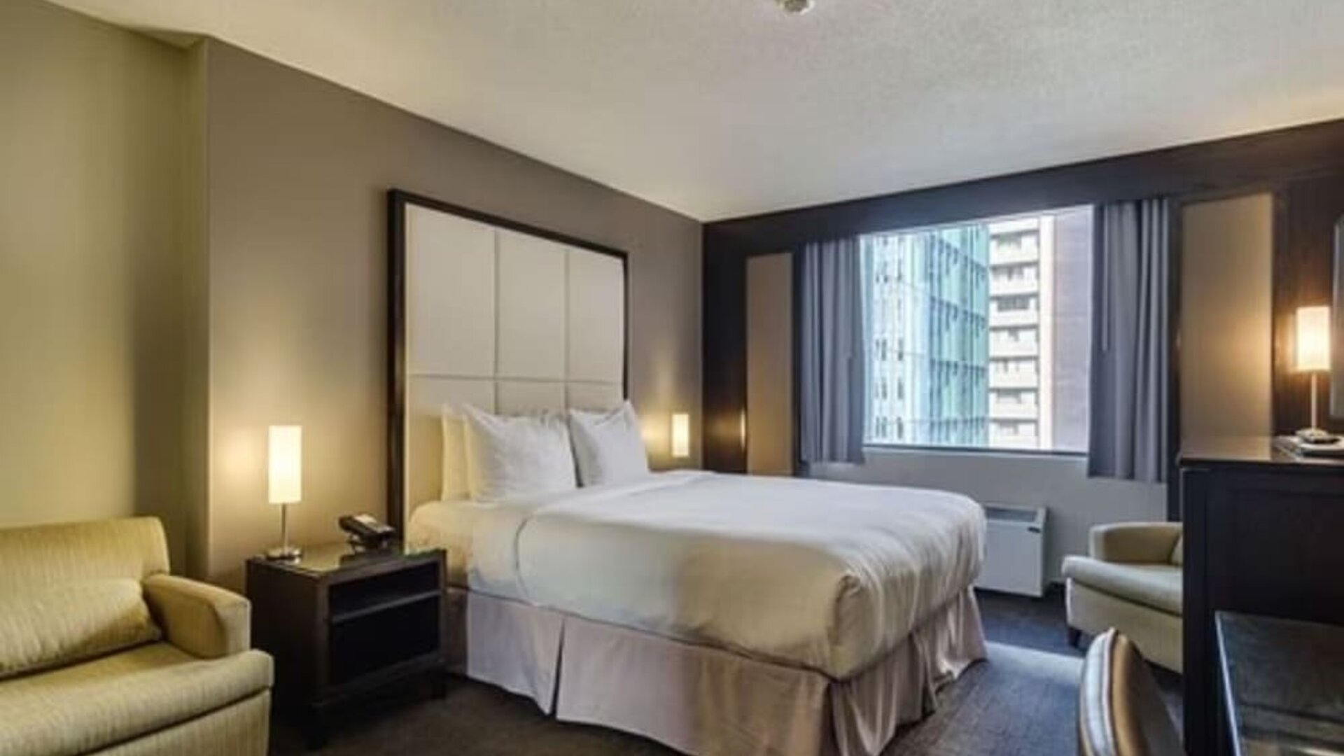 Spacious guest room with a king bed, comfortable seating area, and city views at ARC The Hotel Ottawa.