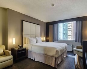 Spacious guest room with a king bed, comfortable seating area, and city views at ARC The Hotel Ottawa.