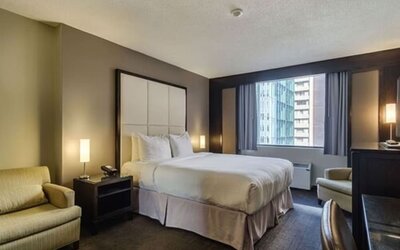 Spacious guest room with a king bed, comfortable seating area, and city views at ARC The Hotel Ottawa.