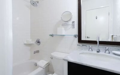 Modern guest bathroom featuring a shower and bathtub combination, spacious vanity, and complimentary bath amenities at ARC The Hotel Ottawa.