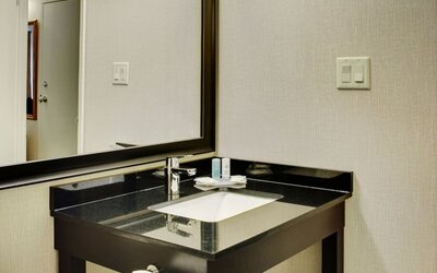 Modern bathroom vanity with granite countertop, large mirror, fresh towels, and complimentary toiletries at Comfort Inn Baie-Comeau.