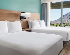 Double queen guest room featuring two plush beds, modern furnishings, and stunning mountain views at Hyatt Place Scottsdale/Old Town.