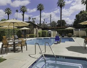 Outdoor swimming pool and whirlpool spa surrounded by lounge seating and shaded patio areas at Courtyard Riverside UCR/Moreno Valley Area.