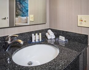 Modern bathroom vanity with granite countertop, premium toiletries, and fresh towels at Courtyard Riverside UCR/Moreno Valley Area.
