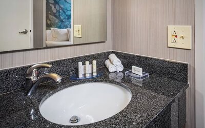 Modern bathroom vanity with granite countertop, premium toiletries, and fresh towels at Courtyard Riverside UCR/Moreno Valley Area.