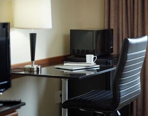 In-room workspace with a desk, ergonomic chair, microwave, mini refrigerator, and coffee service at Comfort Inn Sherbrooke.