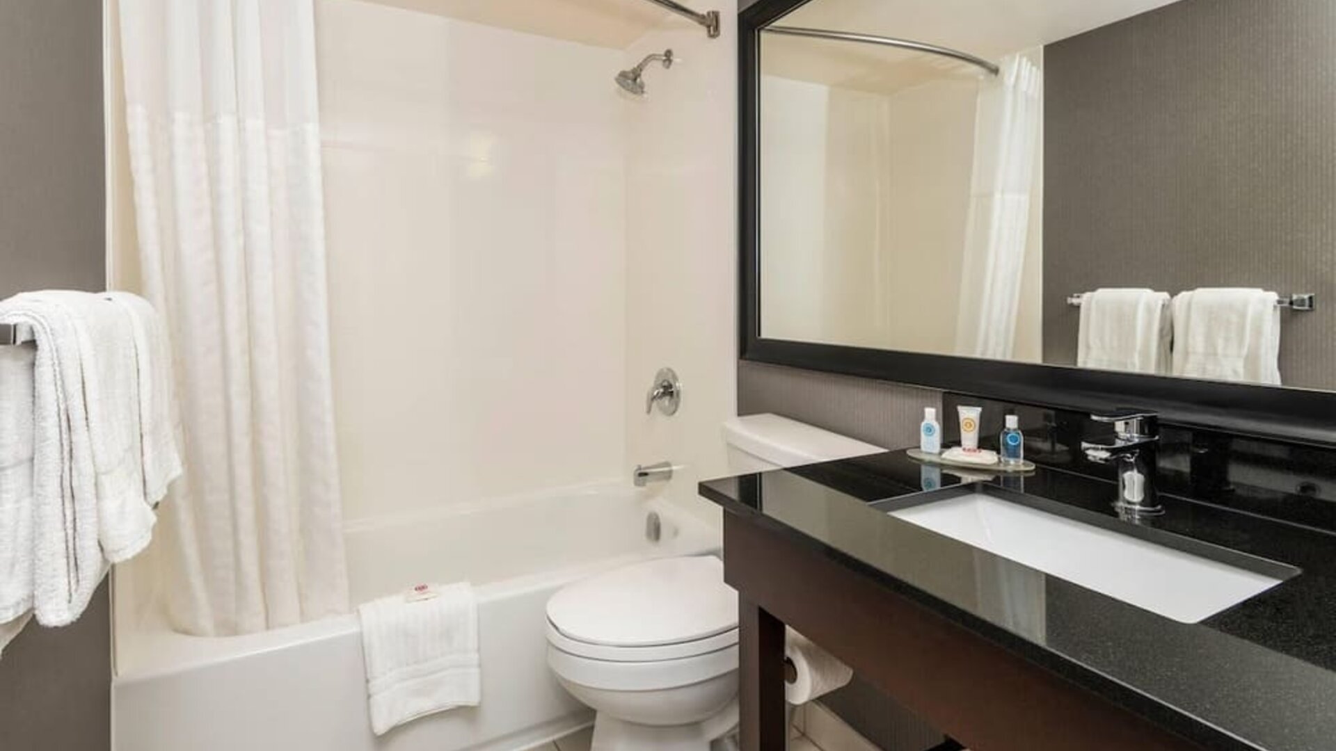 Modern guest bathroom with a shower and bathtub combination, spacious vanity, fresh towels, and complimentary bath amenities at Comfort Inn Sherbrooke.