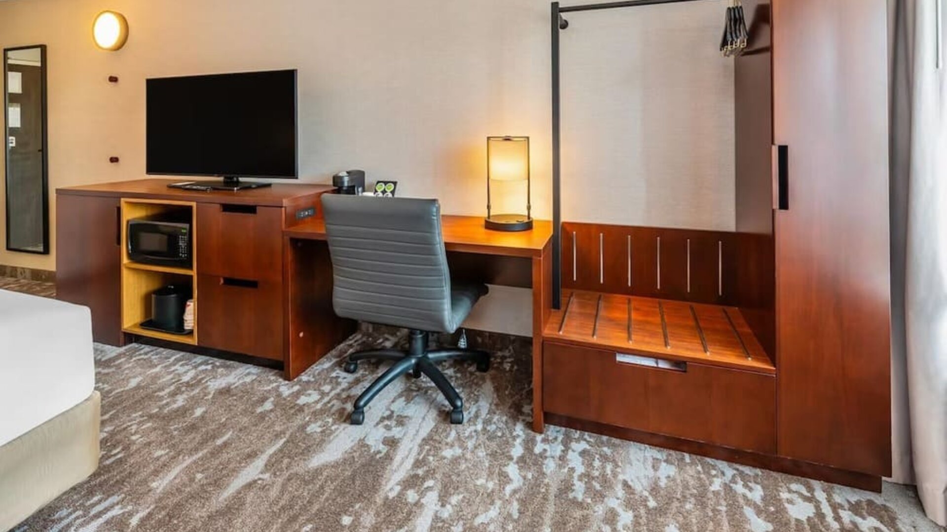 In-room workspace with a desk, ergonomic chair, HDTV, microwave, coffee maker, and luggage rack at Comfort Inn Sudbury Regent Street.