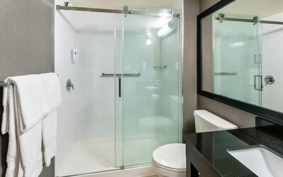 Modern guest bathroom featuring a glass walk-in shower, granite vanity, fresh towels, and contemporary finishes at Comfort Inn Sudbury Regent Street.