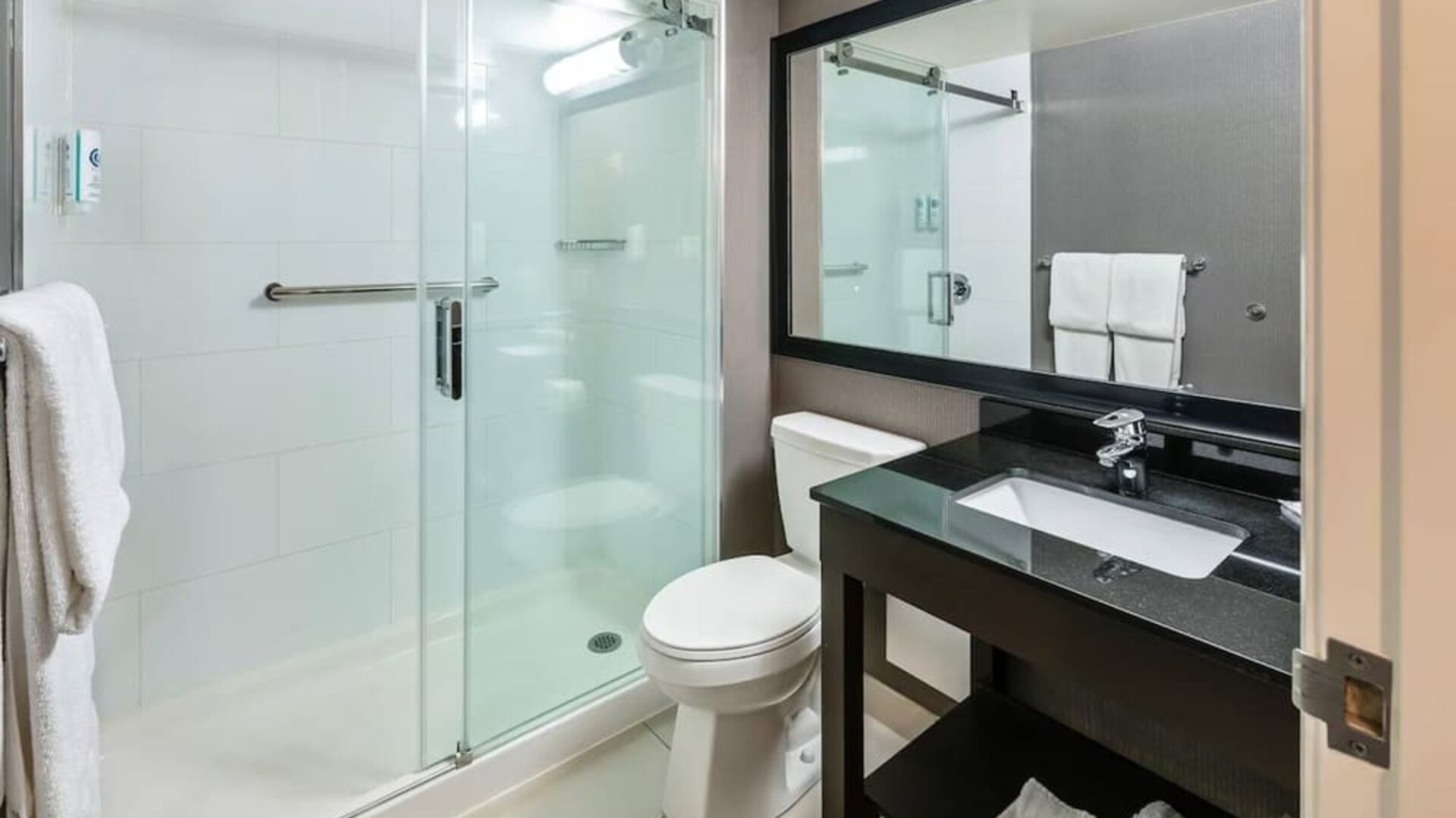 Modern guest bathroom with a glass walk-in shower, granite vanity, fresh towels, and complimentary toiletries at Comfort Inn Sudbury Regent Street.