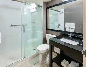Modern guest bathroom with a glass walk-in shower, granite vanity, fresh towels, and complimentary toiletries at Comfort Inn Sudbury Regent Street.