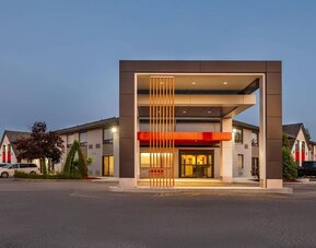 Exterior view of Comfort Inn Sudbury Regent Street featuring ample guest parking and a covered hotel entrance.