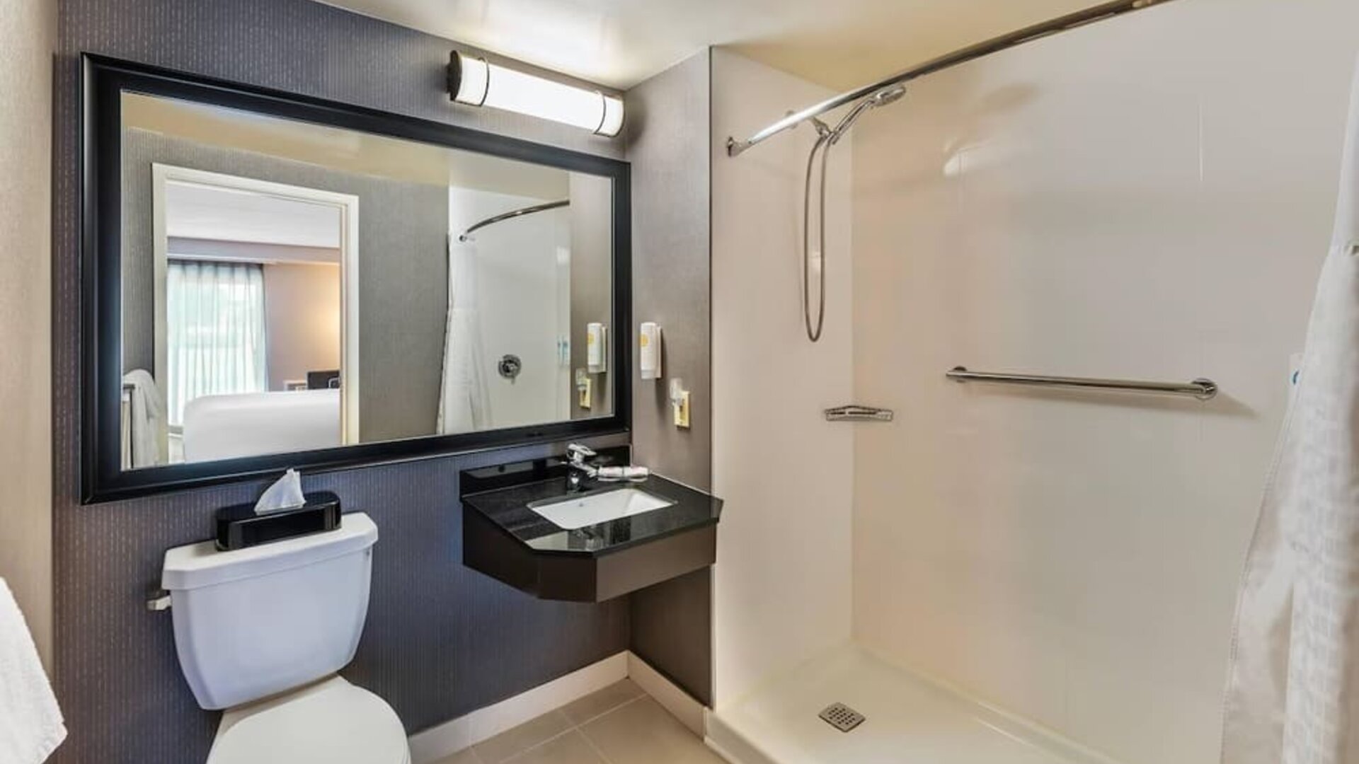 Accessible guest bathroom with a roll-in shower, grab bars, granite vanity, and fresh towels at Comfort Inn Sudbury Regent Street.