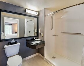 Accessible guest bathroom with a roll-in shower, grab bars, granite vanity, and fresh towels at Comfort Inn Sudbury Regent Street.