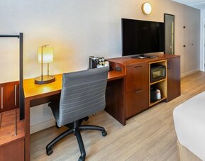In-room workspace with a desk, ergonomic chair, HDTV, microwave, coffee maker, and luggage storage at Comfort Inn Sudbury Regent Street.