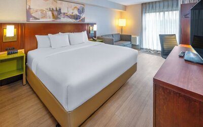 Spacious king guest room with plush bedding, seating area, and work desk at Comfort Inn Sudbury East.